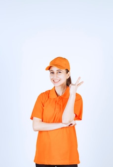 Courrier féminin portant l'uniforme orange et la casquette montrant le signe de la paix