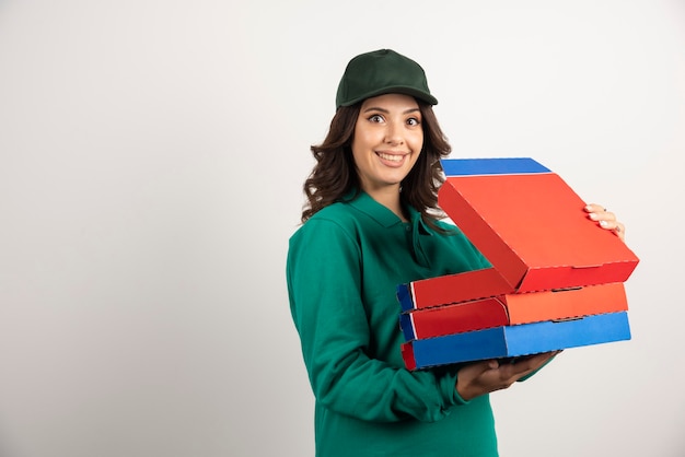 Courrier féminin positif tenant une boîte à pizza ouverte.