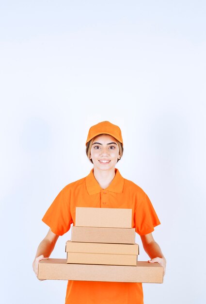 Courrier féminin en uniforme orange tenant un stock de colis en carton