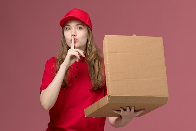 Courrier féminin en uniforme rouge tenant la boîte de nourriture et l'ouvrir sur rose, un service uniforme livrant des travailleurs