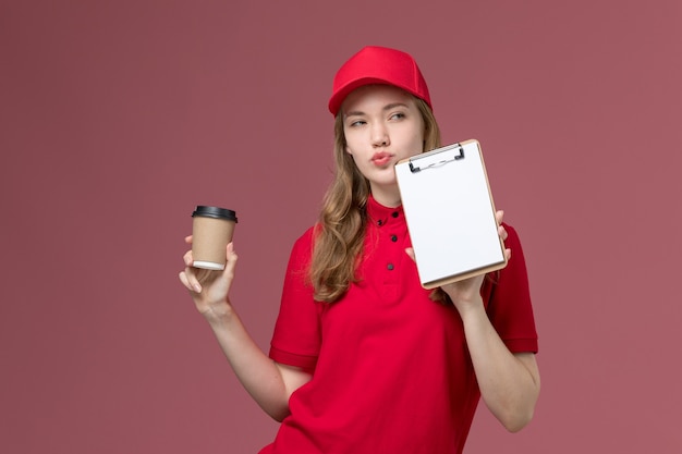 Courrier féminin en uniforme rouge tenant le café et le bloc-notes sur rose, prestation de services de travail uniforme