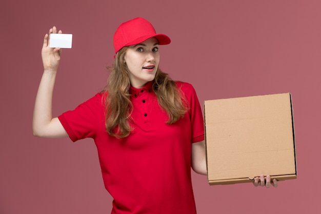 Courrier féminin en uniforme rouge tenant une carte blanche et une boîte de nourriture sur rose, service uniforme