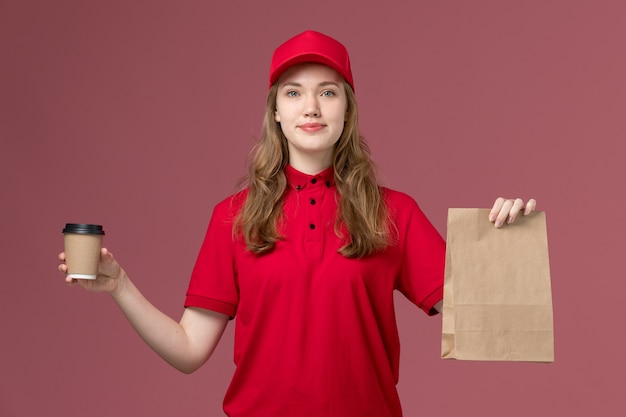 Courrier féminin en uniforme rouge tenant une tasse de café avec un paquet de nourriture sur rose, travail de livraison de service uniforme