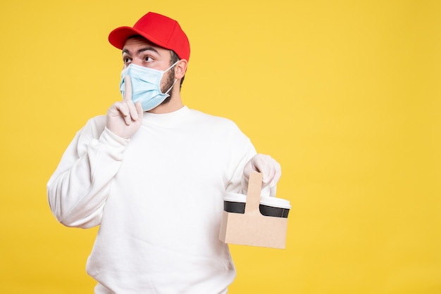 courrier mâle en masque tenant un café de livraison sur jaune