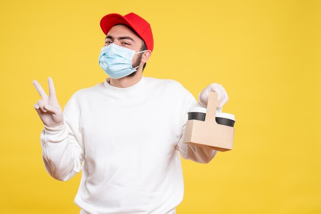 courrier mâle en masque tenant un café de livraison sur jaune