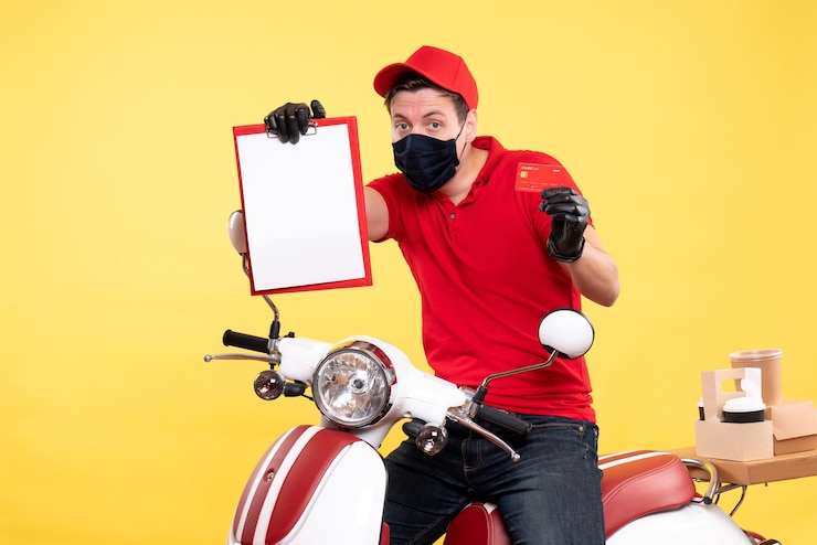 Photo gratuit courrier masculin vue de face dans un masque tenant une note de fichier et une carte bancaire sur jaune
