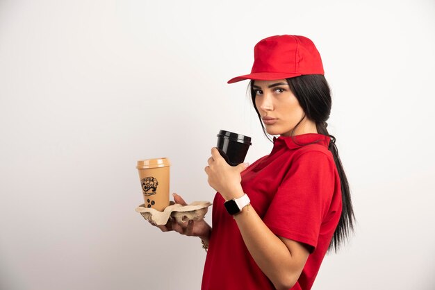 Courrier sérieux posant avec deux tasses de café sur fond blanc. Photo de haute qualité