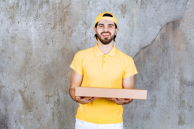 Courrier en uniforme jaune tenant une boîte à pizza à emporter