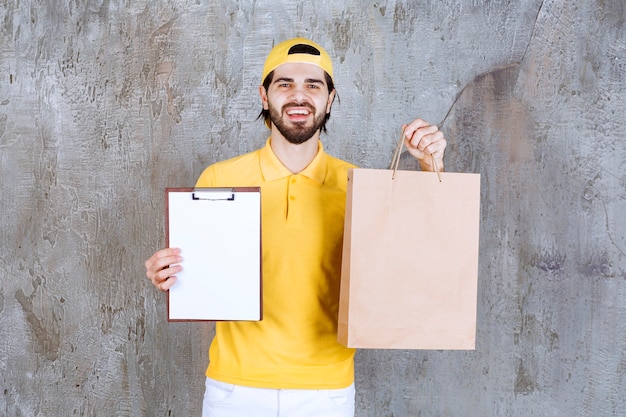 Courrier en uniforme jaune tenant un sac en carton et demandant la signature