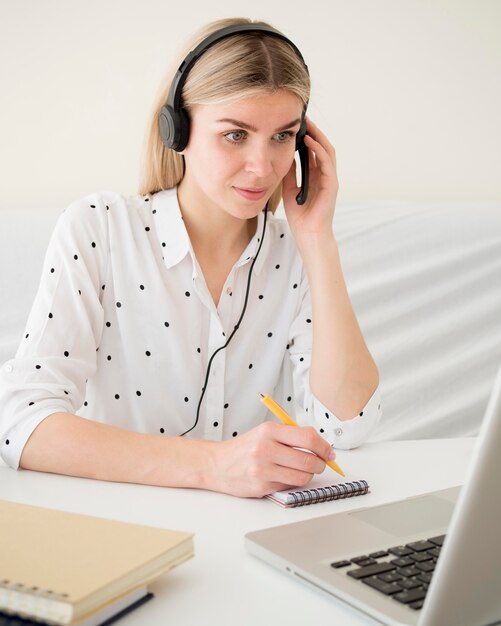 Cours en ligne avec une étudiante tenant ses écouteurs