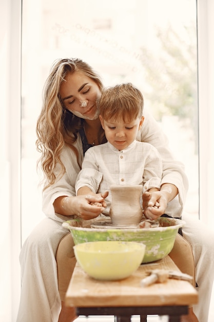 Cours De Poterie. Jeune Mère Caucasienne Enseignant Son Fils. Fils Faisant Un Pot En Argile Sur Un Tour De Potier.