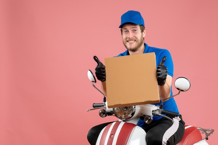 Photo gratuit coursier mâle vue de face assis sur un vélo et tenant une boîte à pizza sur le rose