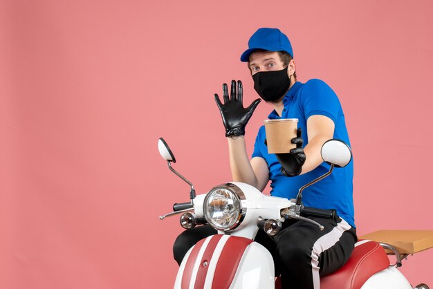 Coursier mâle vue de face assis sur un vélo et tenant une grande tasse de café sur le rose