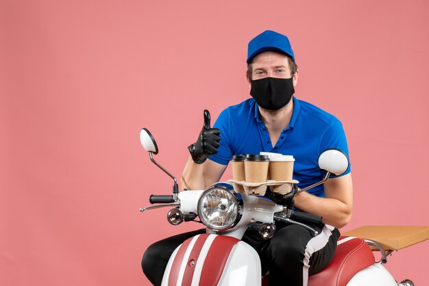 Coursier mâle vue de face assis sur un vélo et tenant des tasses à café sur le rose