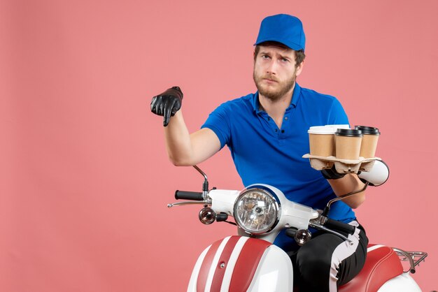 Coursier mâle vue de face assis sur un vélo et tenant des tasses à café sur le rose