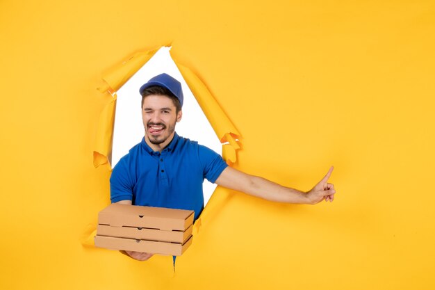 Coursier mâle vue de face tenant des boîtes à pizza sur un espace jaune