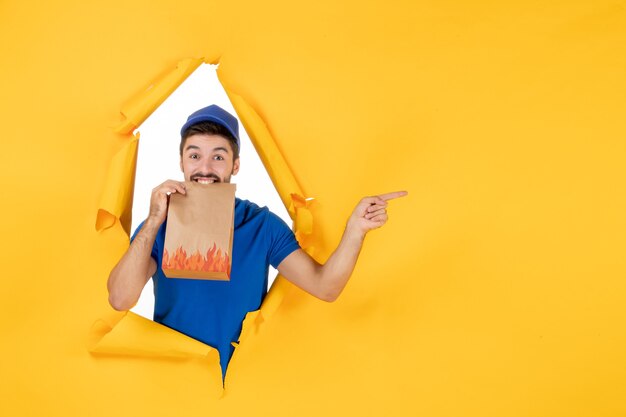 Coursier mâle vue de face en uniforme bleu avec emballage alimentaire sur espace jaune