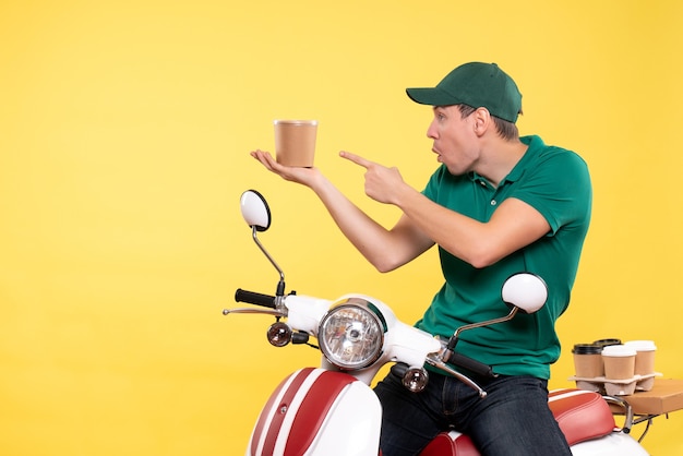 Photo gratuite coursier mâle vue de face en uniforme tenant une tasse de café sur jaune