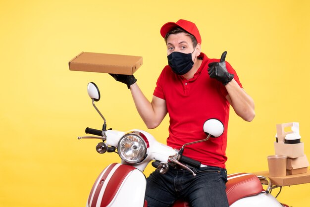 Coursier mâle vue de face à vélo en masque avec boîte de nourriture sur jaune