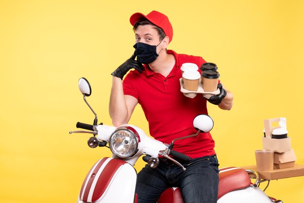 Coursier mâle vue de face à vélo en masque avec café sur jaune