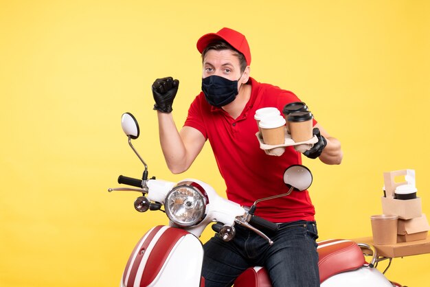 Coursier mâle vue de face à vélo en masque avec café sur jaune