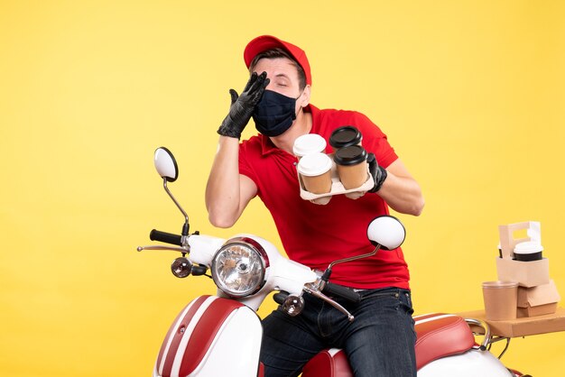 Coursier mâle vue de face à vélo en masque avec café sur jaune