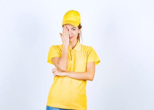 Coursière en uniforme jaune fermant une partie de son visage et de ses yeux.