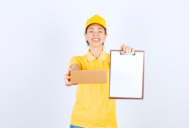 Coursière en uniforme jaune livrant le colis en carton et demandant de signer la liste.