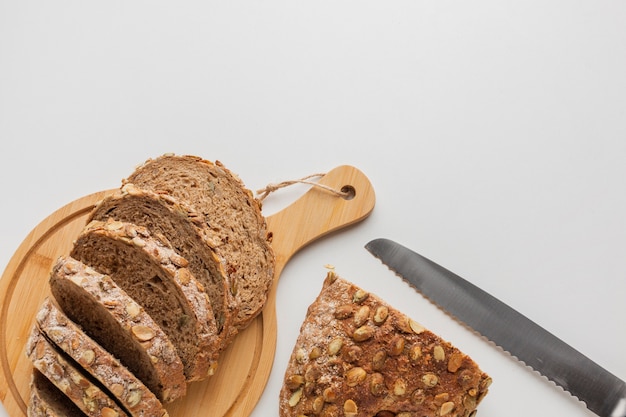 Photo gratuite couteau et tranches de pain sur une planche de bois