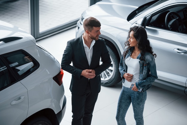 Écouter attentivement. Clientèle féminine et homme d'affaires barbu élégant et moderne dans le salon automobile