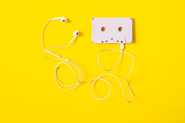 Écouteur blanc connecté à une cassette sur fond jaune