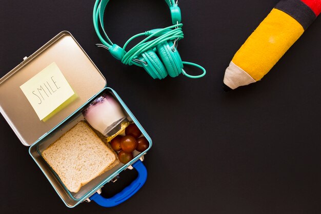 Écouteurs et étui à crayons près de la boîte à lunch