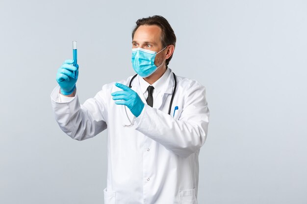 Covid-19, prévention du virus, travailleurs de la santé et concept de vaccination. Un médecin enthousiaste du laboratoire de la clinique a développé un vaccin contre le coronavirus, porte un masque médical et des gants, l'air ravi du tube à essai