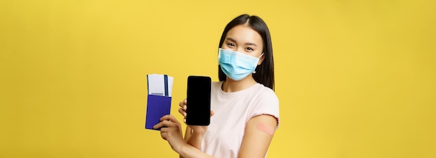 Photo gratuite covid et concept de tourisme femme asiatique souriante vaccinée montrant pas d'interface d'application d'écran de smartphone