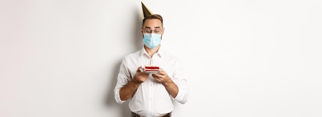 Covid distanciation sociale et célébration homme regardant excité par le gâteau d'anniversaire portant un masque médical fr