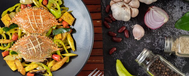 Crabe frit au curry en poudre dans une assiette avec poivrons et tomates.