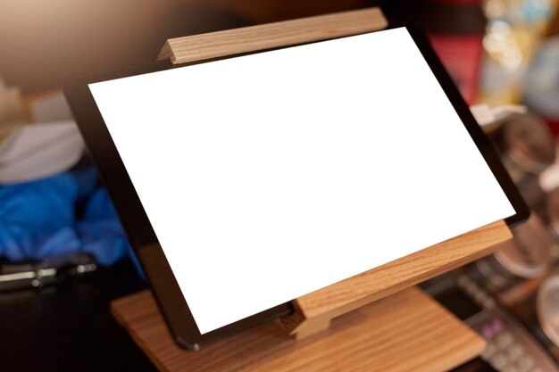 Écran blanc blanc de tablette numérique sur support de tablette en bois