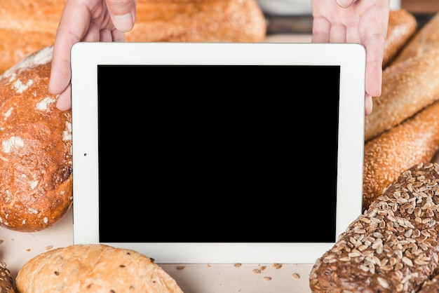 Écran blanc montrant la main avec tablette numérique parmi le pain cuit