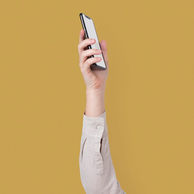 Écran de smartphone vierge isolé en studio avec main levée