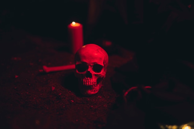 Crâne et bougie dans une lumière rouge foncé