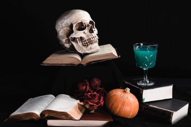 Crâne humain avec boisson verte et livres