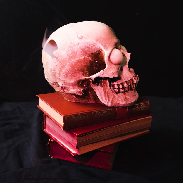Crâne avec la nuque fumée sur les livres