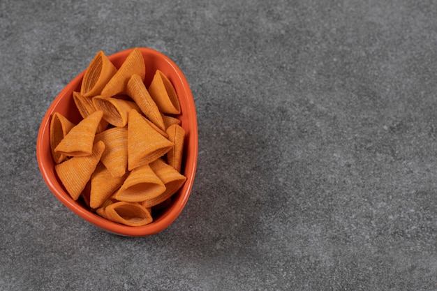 Craquelins en forme de triangle dans un bol orange.