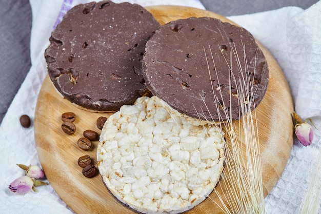 Photo gratuite craquelins de riz et de chocolat sur une plaque en bois avec une nappe.