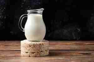 Photo gratuite craquelins de riz et pot en verre de lait sur table en bois.