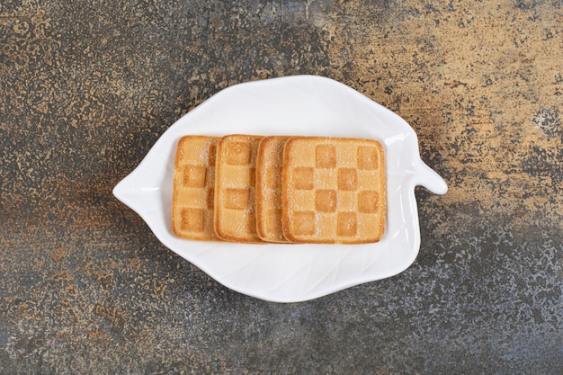 Craquelins sucrés carrés sur assiette en forme de feuille.