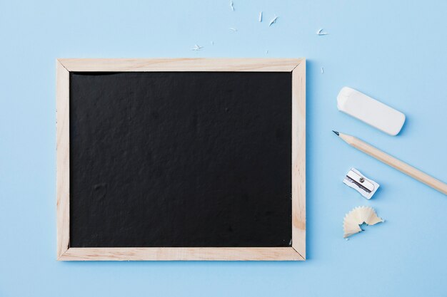 Crayon et caoutchouc près de taille-crayon et tableau noir