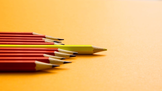 Crayon de couleur jaune se trouvant entre un crayon rouge sur fond jaune