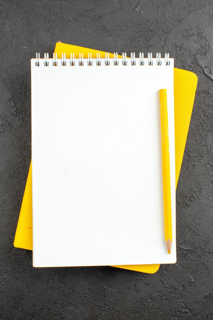 Photo gratuit crayon jaune de bloc-notes en spirale de vue de dessus sur le noir