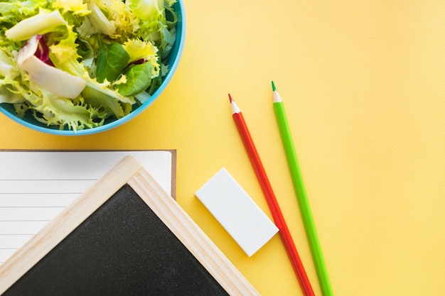 Crayons et caoutchouc près du tableau et de la salade